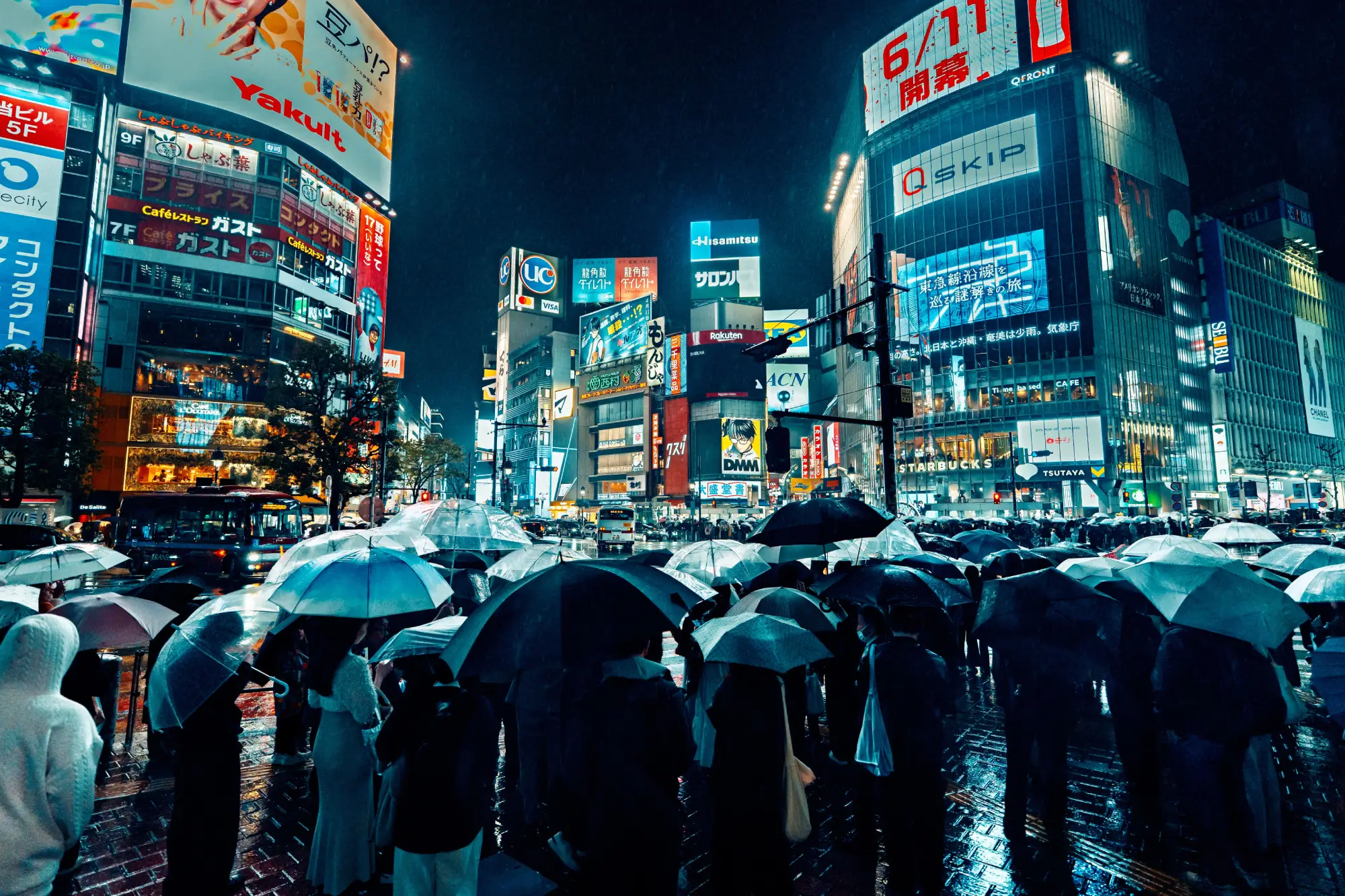 Gruča ljudi z dežniki na trgu v Tokiu v deževnem vremenu