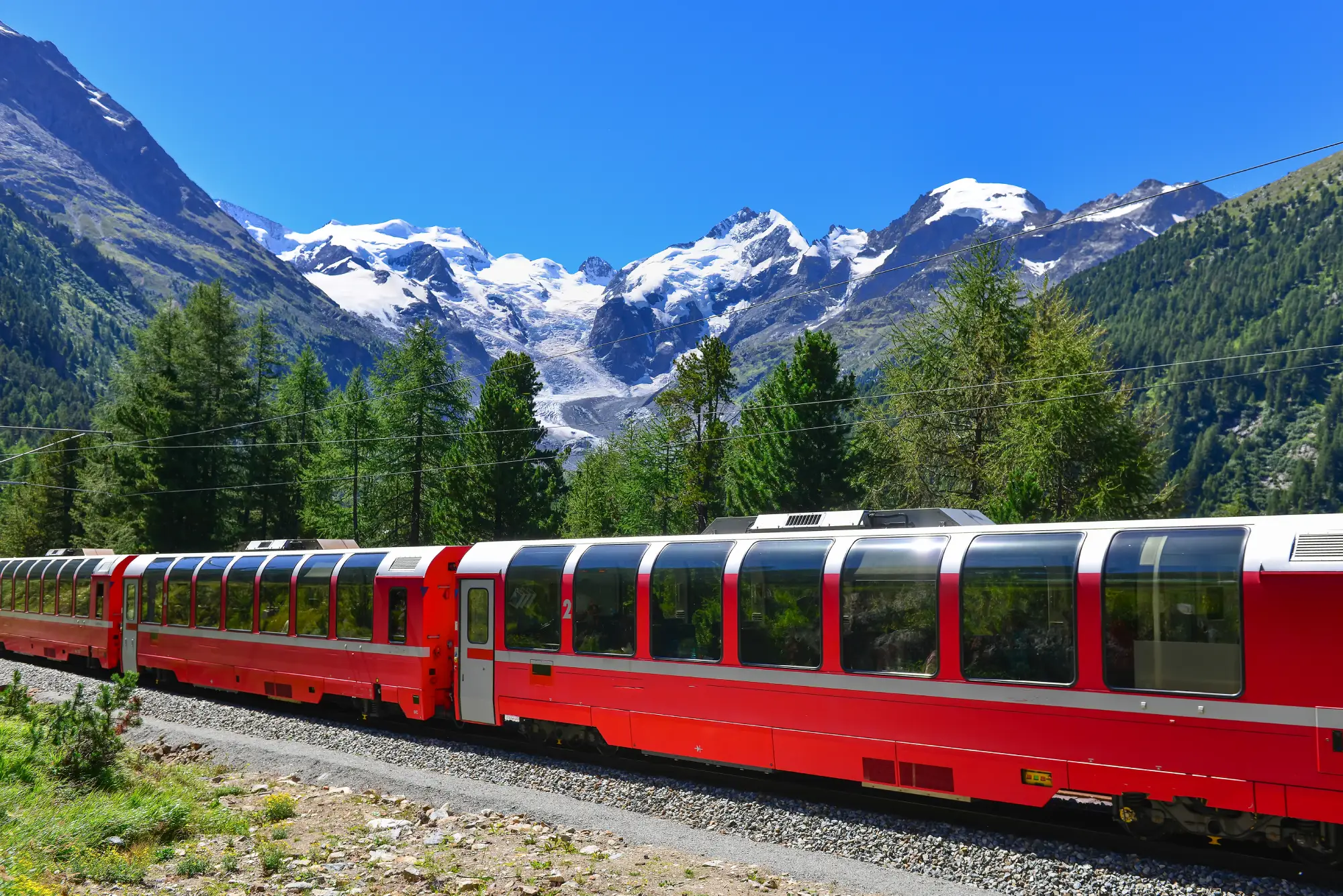 Rdeč panoramski vlak v gozdu v Alpah