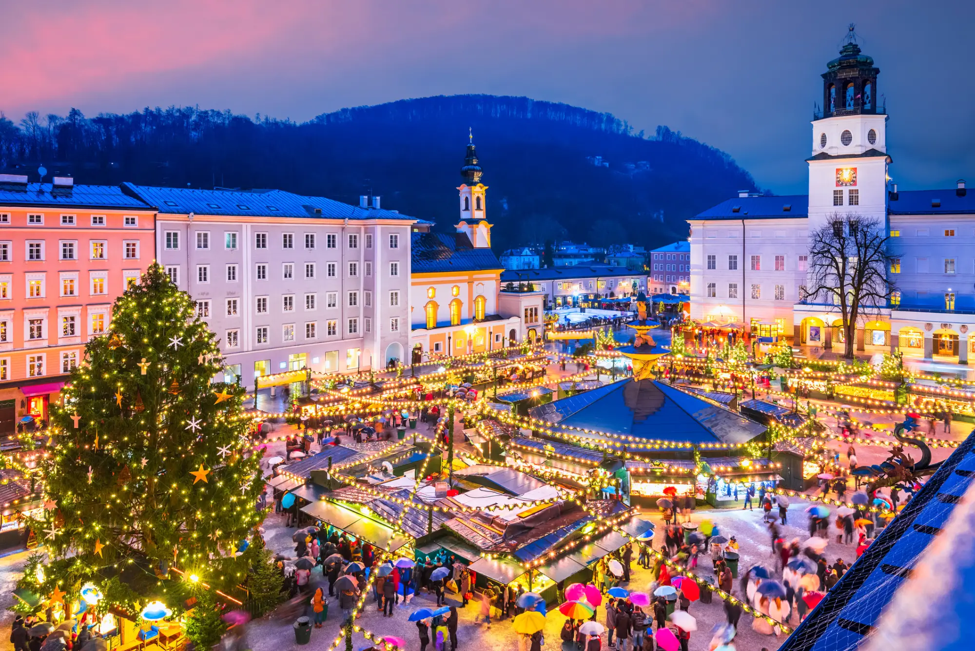 Adventni sejem na trgu Domplatz v Salzburgu s praznično razsvetljavo in božičnim drevesom.