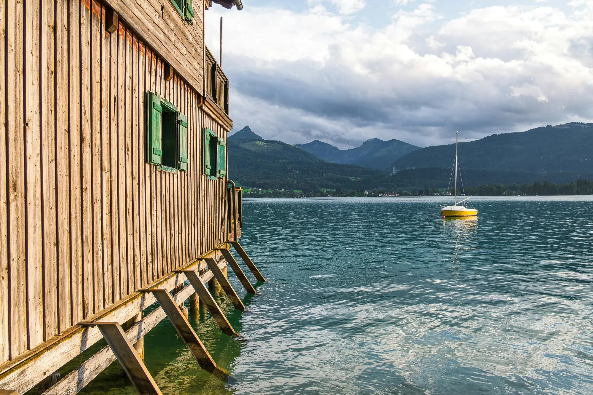 Lesena koča ob jezeru na katerem je čoln v Dolomitih