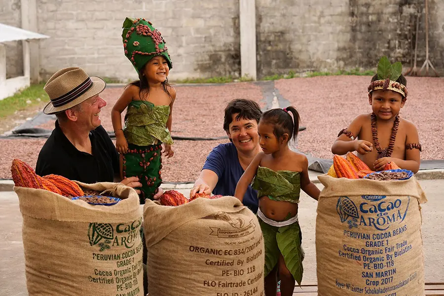 Josef in Ulrike Zotter z lokalnimi pridelovalci kakava ob vrečah ekološko pridelanih kakavovih zrn na Madagaskarju
