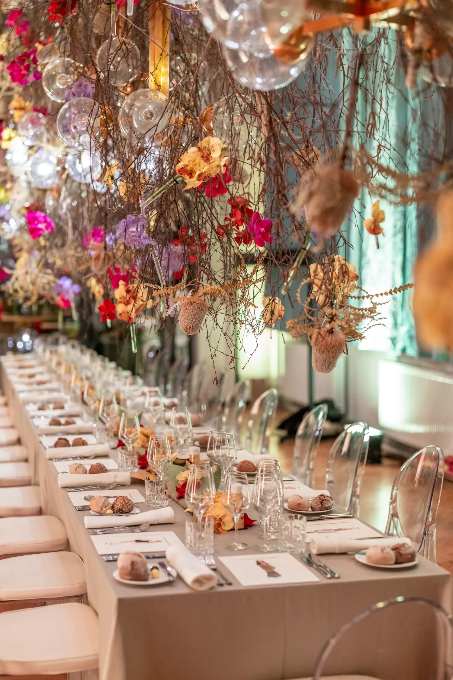 Elegantly decorated long event table with hanging floral installation at a luxury venue in Slovenia.