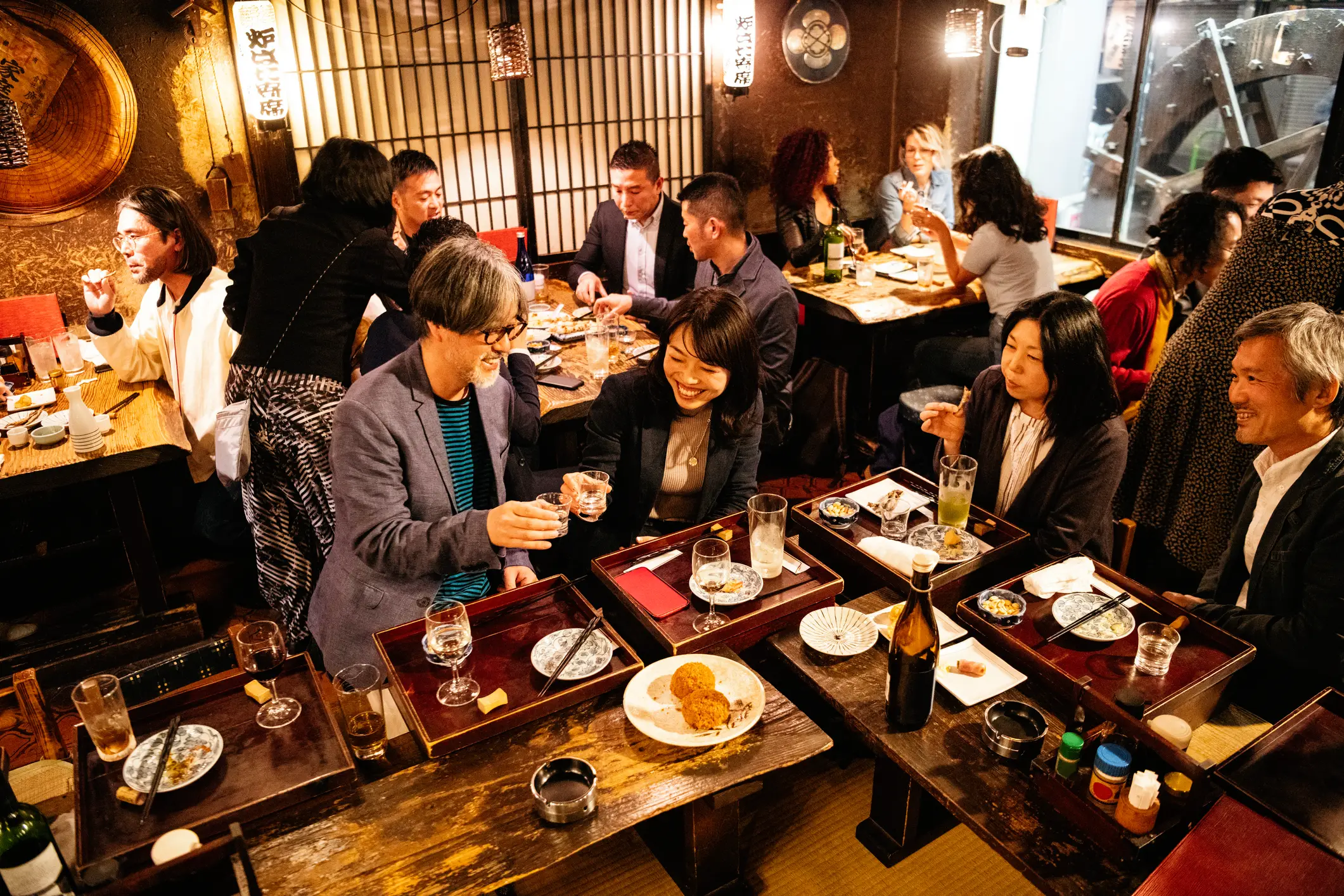 Prijatelji ob večerji in pijači v tradicionalni japonski izakaya restavraciji