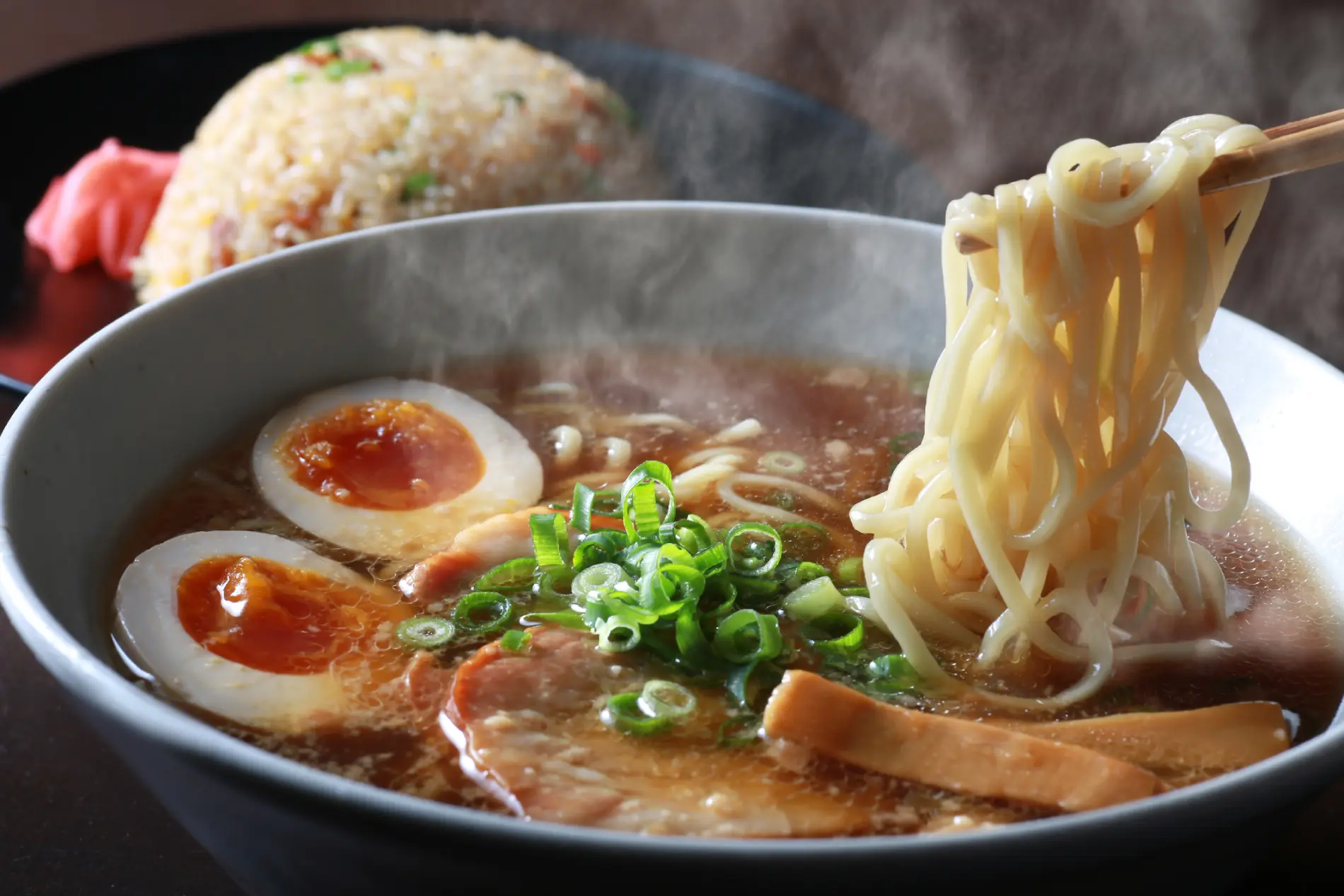 Skleda japonske juhe ramen z rezanci, jajcem, mesom in mlado čebulo.