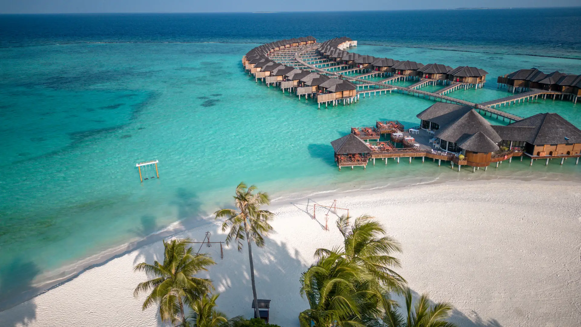 Pogled na bungalove na Maldivih v kristalno čisti vodi.