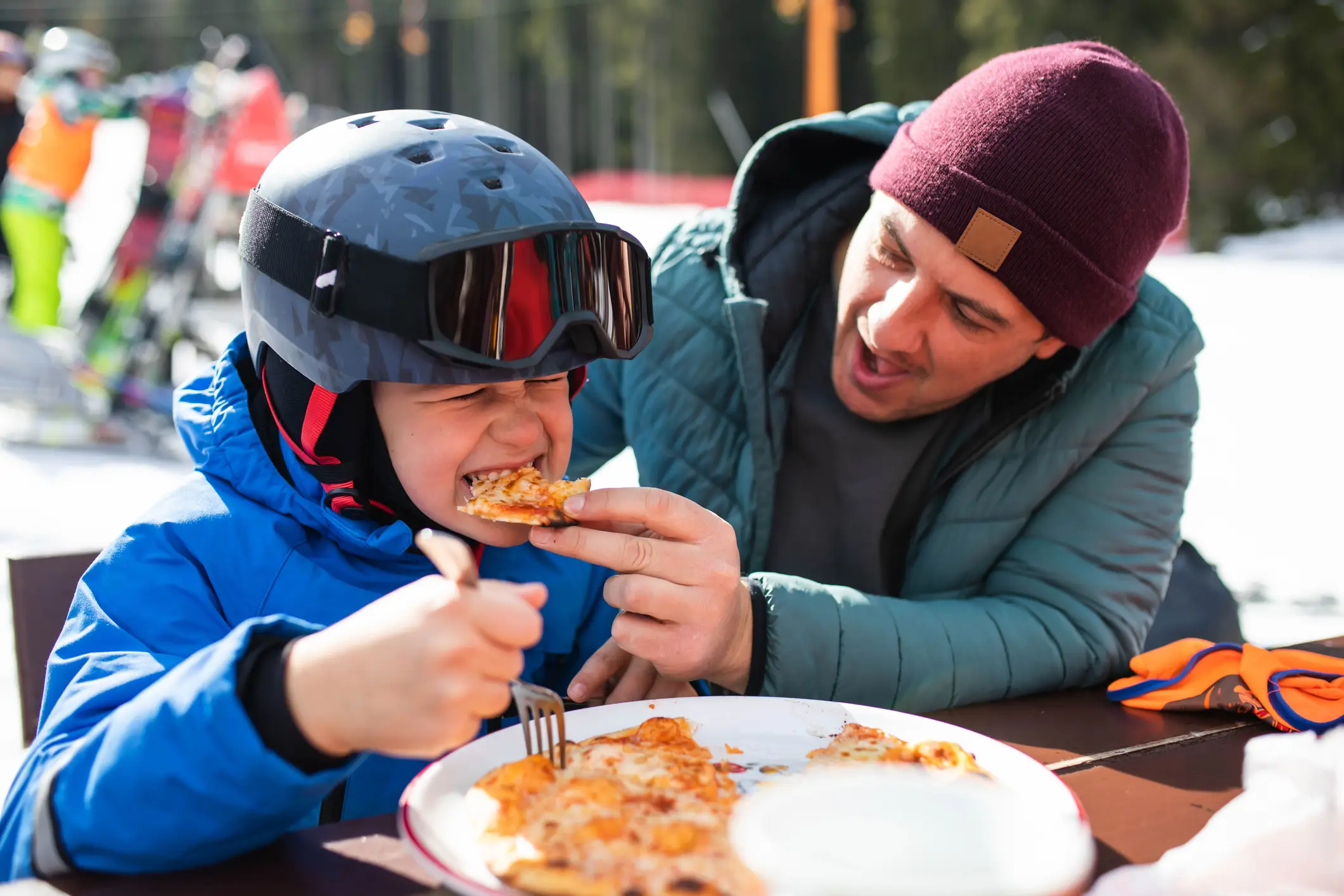 Otrok uživa v pici na prostem med družinskim smučarskim kosilom