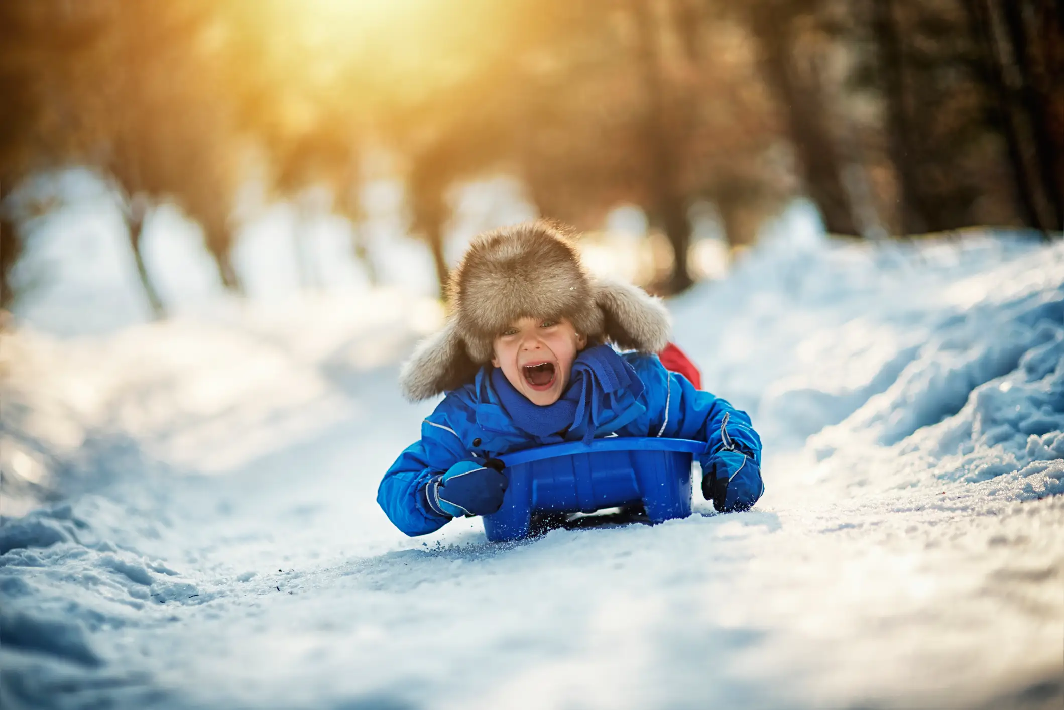 Otrok uživa v sankanju na zasneženi progi