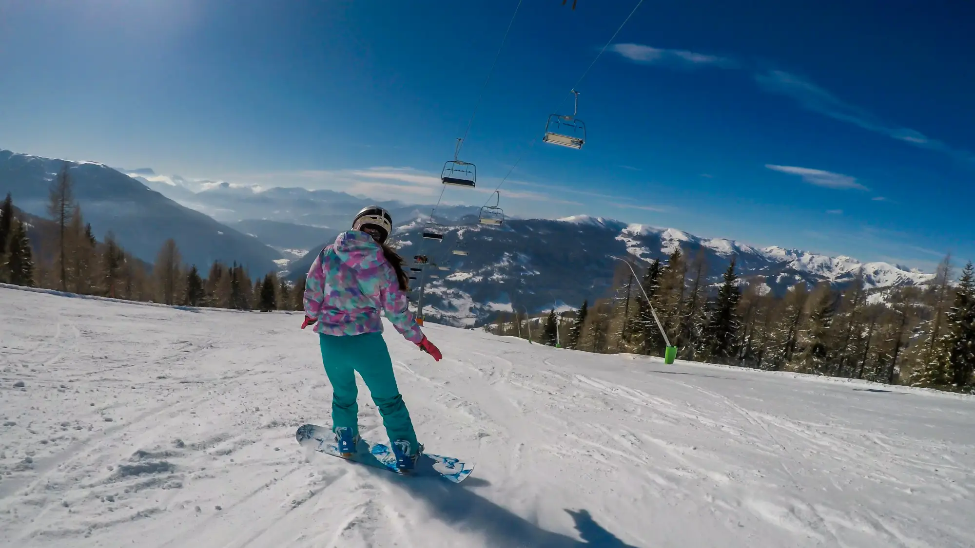Smučarka v barvnem kombinezonu snowboarda na avstrijskem smučišču