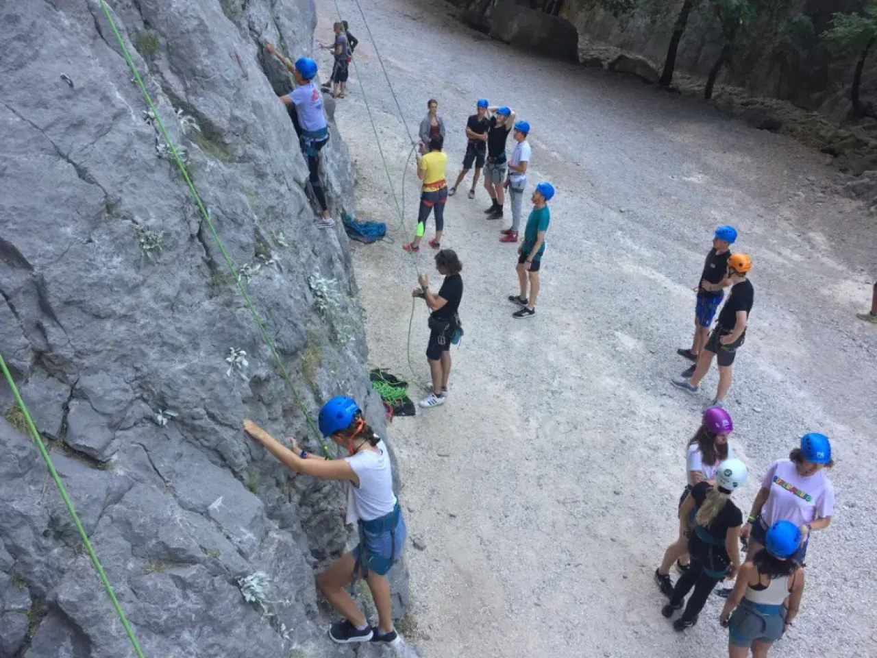 Skupina najstnikov pri Teen Adventure programu preizkuša plezanje po naravni skalni steni