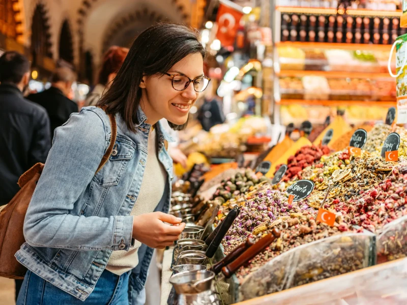 Popotnica raziskuje barvito tržnico začimb v Istanbulu in občuduje raznoliko ponudbo dišav, čajev in suhega sadja.