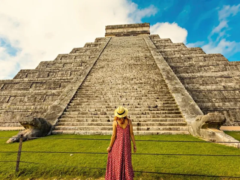 Turistka stoji pred mogočno stopničasto piramido Kukulkan v Chichén Itzá, Mehika.