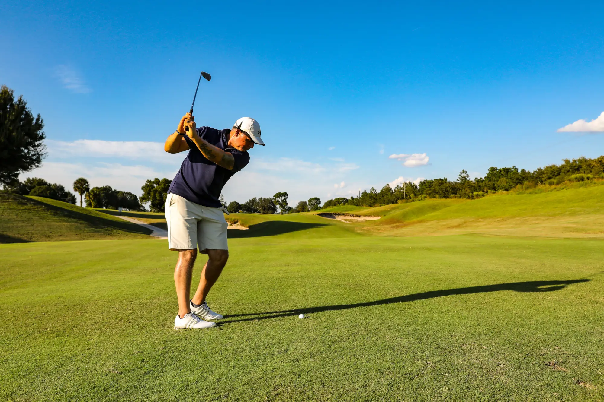 Golfist udarja žogico v sončnem vremenu